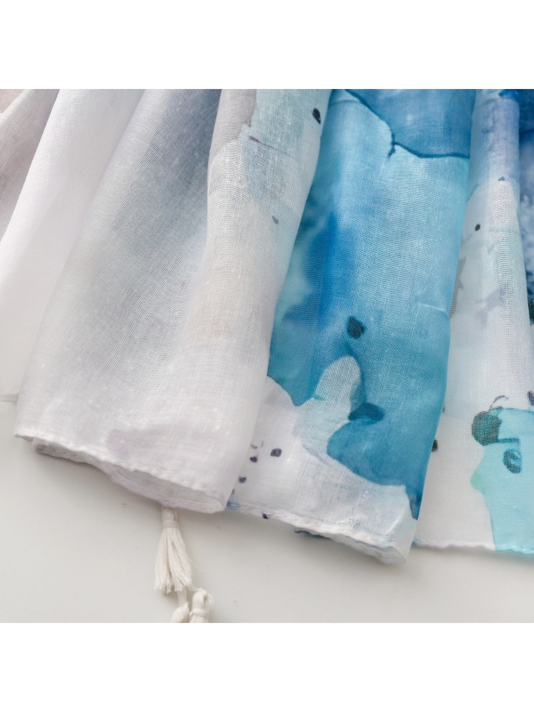 Close-up of the scarf's blue abstract pattern and white corner tassel