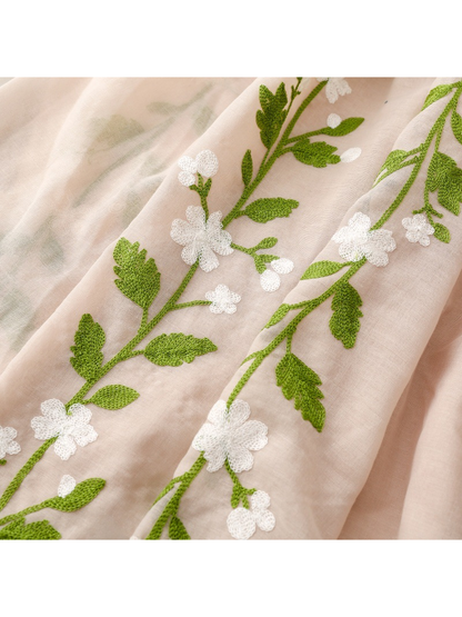 Close-up of green leafy vines and white floral embroidery on the Beige scarf