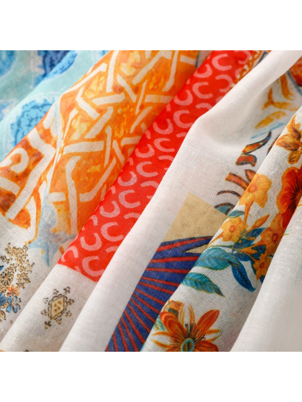 Close-up of orange geometric, red curved and floral scarf patterns