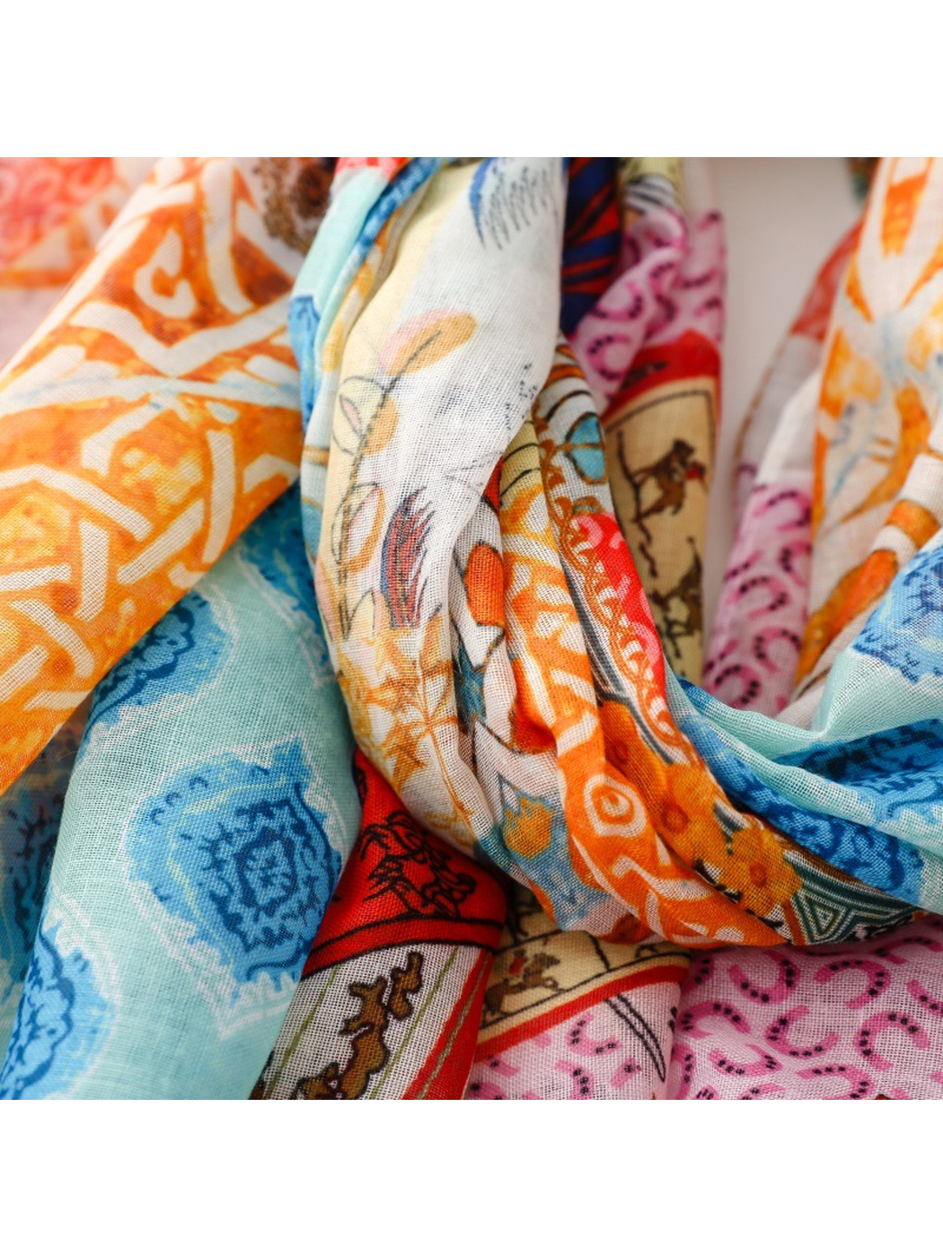 Close-up of layered scarf folds with blue, orange, pink and red motifs