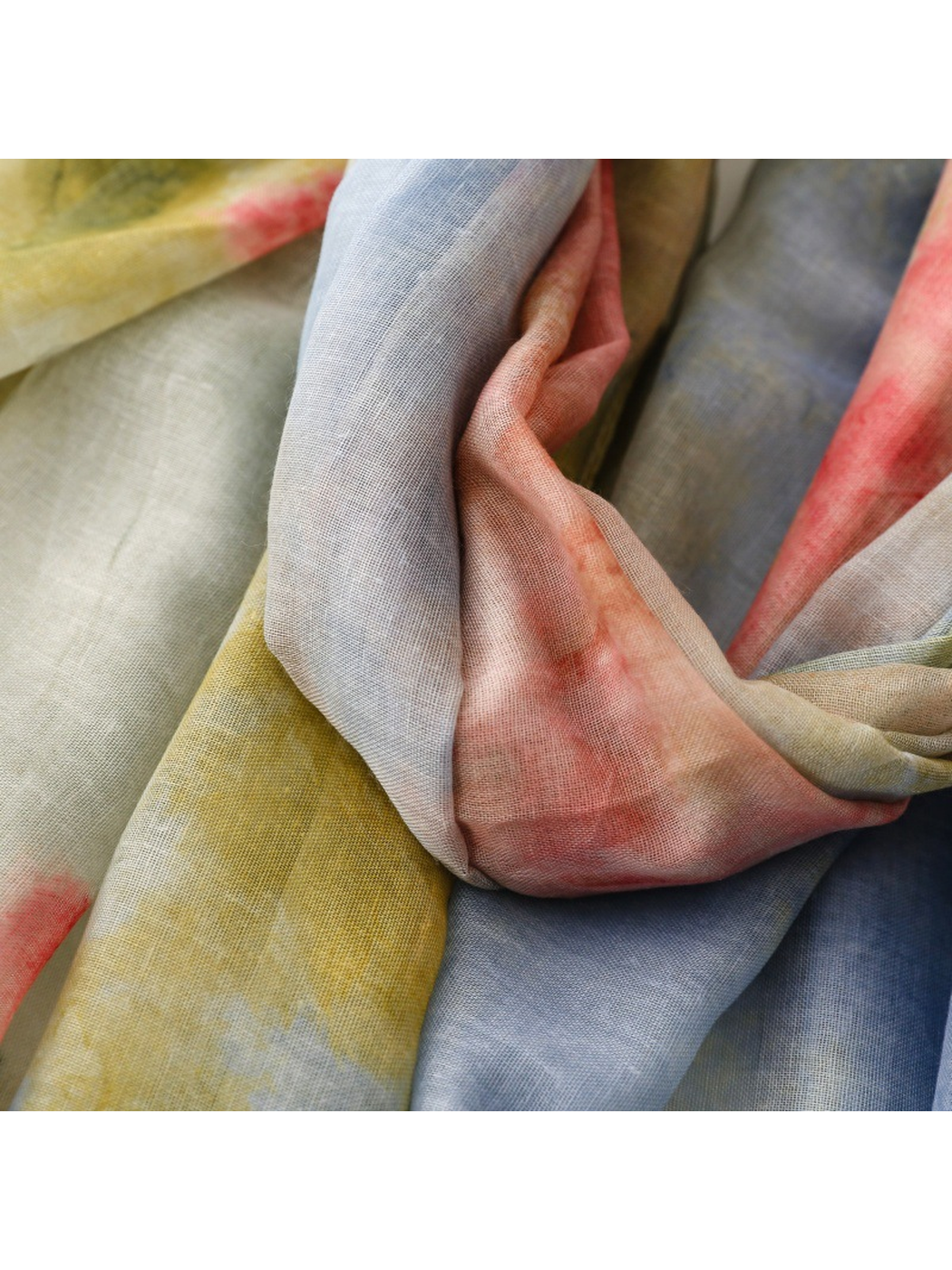 Close-up of the scarf draped in blue, coral and muted yellow-green folds