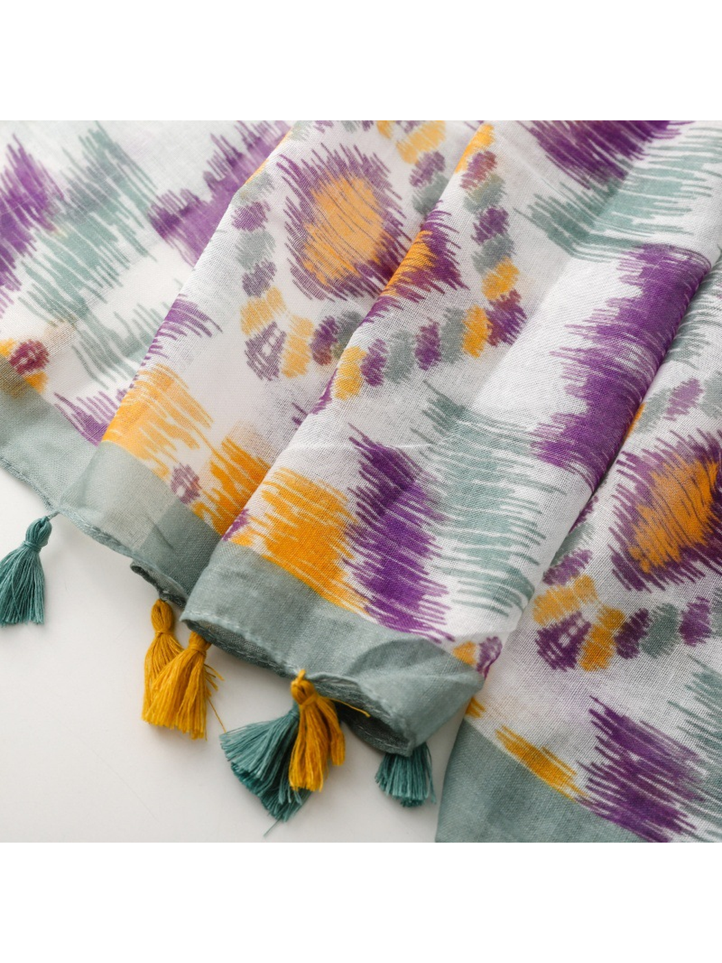Close-up of the scarf's gray-green border and mustard and teal tassels
