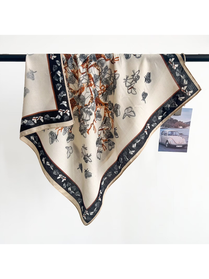 Cream butterfly-pattern square scarf draped over a display rail