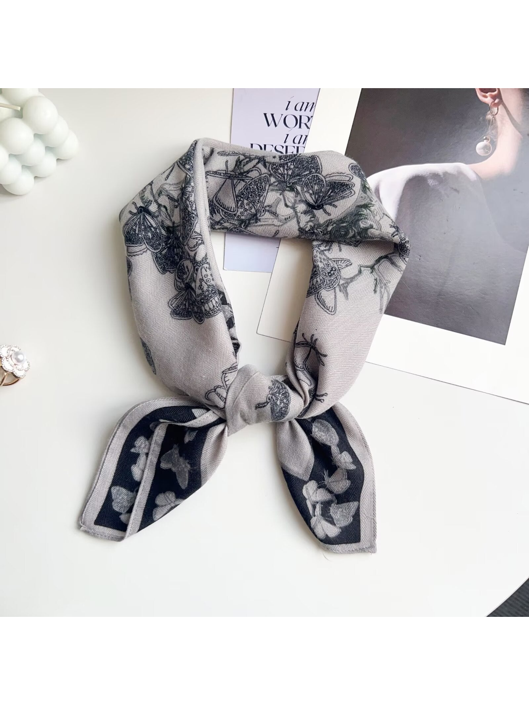 Light gray butterfly-pattern square scarf arranged in a knotted loop