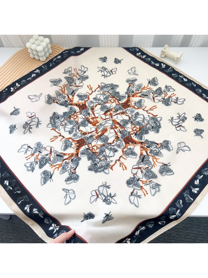 Cream butterfly-pattern square scarf laid flat with rust-orange branches and a dark border