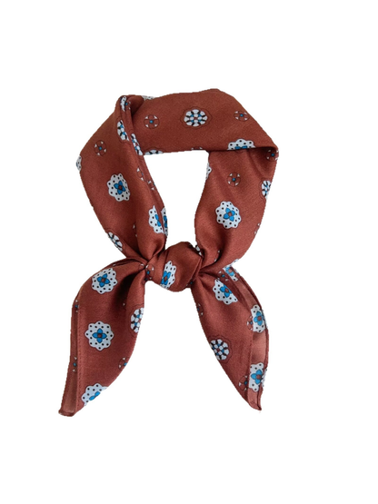 Orange red medallion-pattern square scarf tied in a dimensional loop