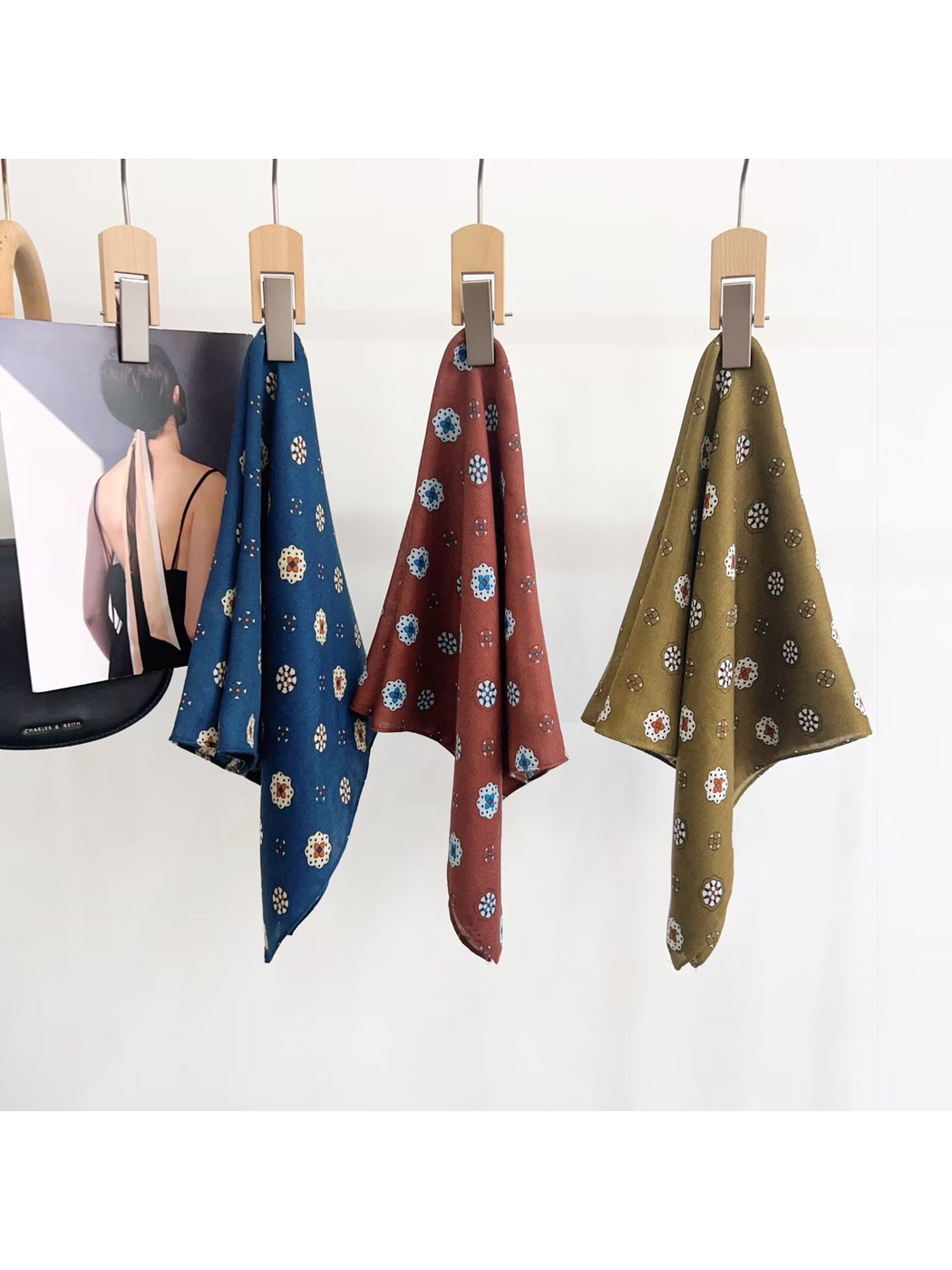 Three medallion-pattern square scarves displayed in blue, rust and olive tones
