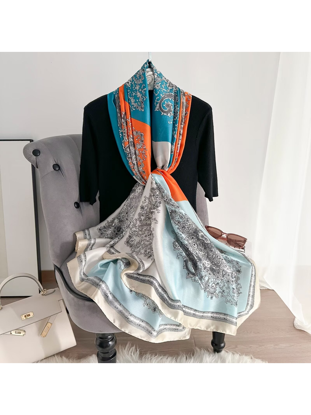 Teal and orange paisley scarf looped and knotted over a chair