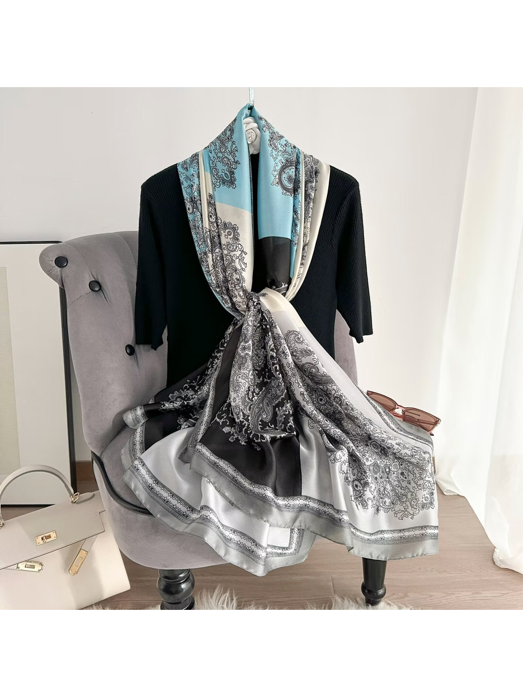 Light blue, ivory and black paisley scarf looped and knotted over a chair