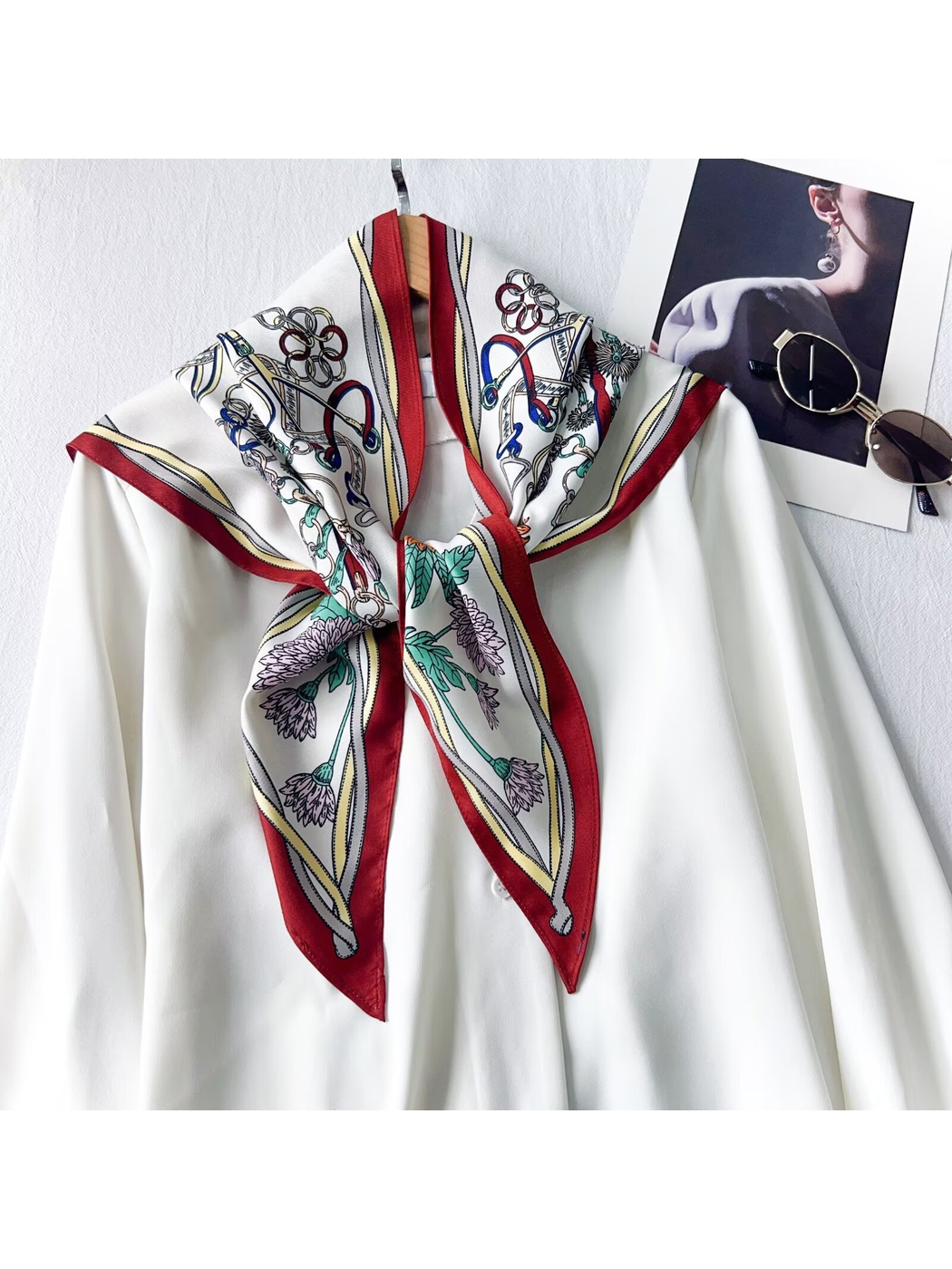 Burgundy-border floral and equestrian-print triangle scarf tied over a white blouse