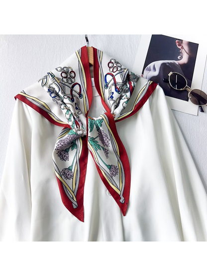 Burgundy-border floral and equestrian-print triangle scarf tied over a white blouse