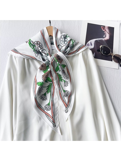 White triangle scarf with blush trim and floral print tied over a white blouse