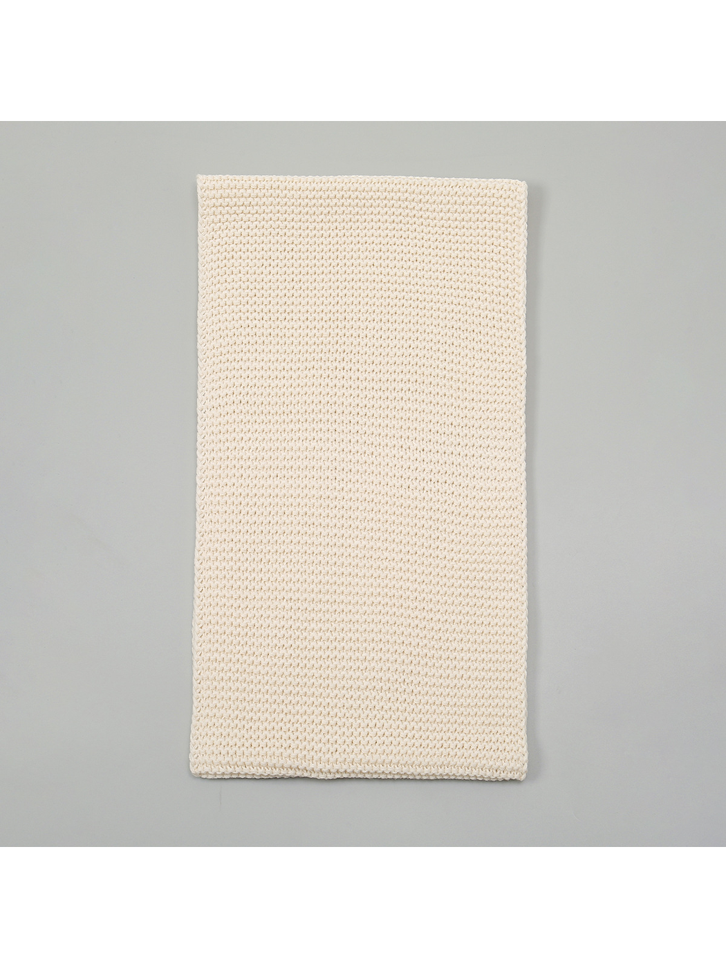 Beige knit infinity scarf laid flat to show its rectangular loop shape