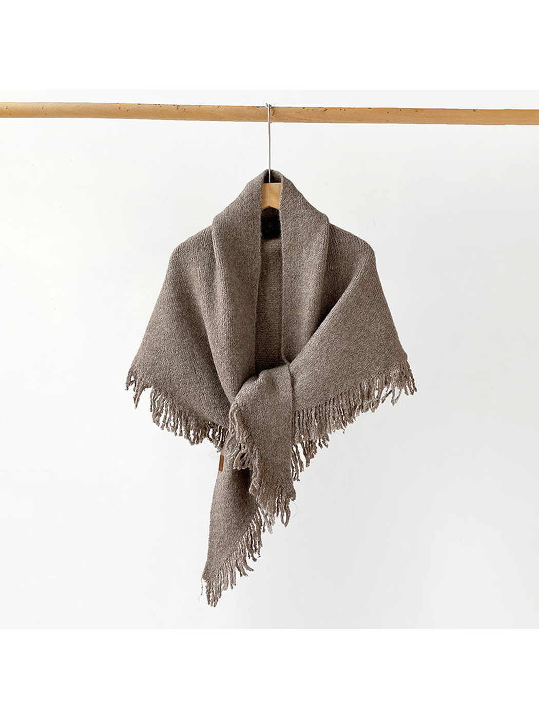 Brown fringed scarf draped and knotted on a hanger