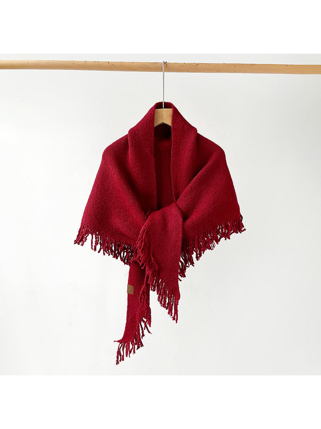 Red fringed scarf draped and knotted on a hanger