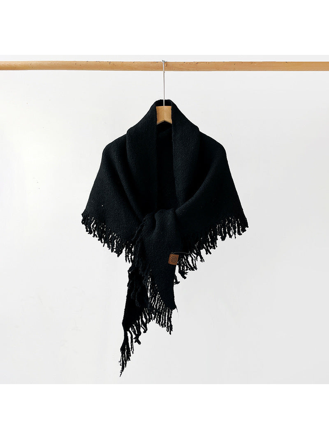 Black fringed scarf draped and knotted on a hanger