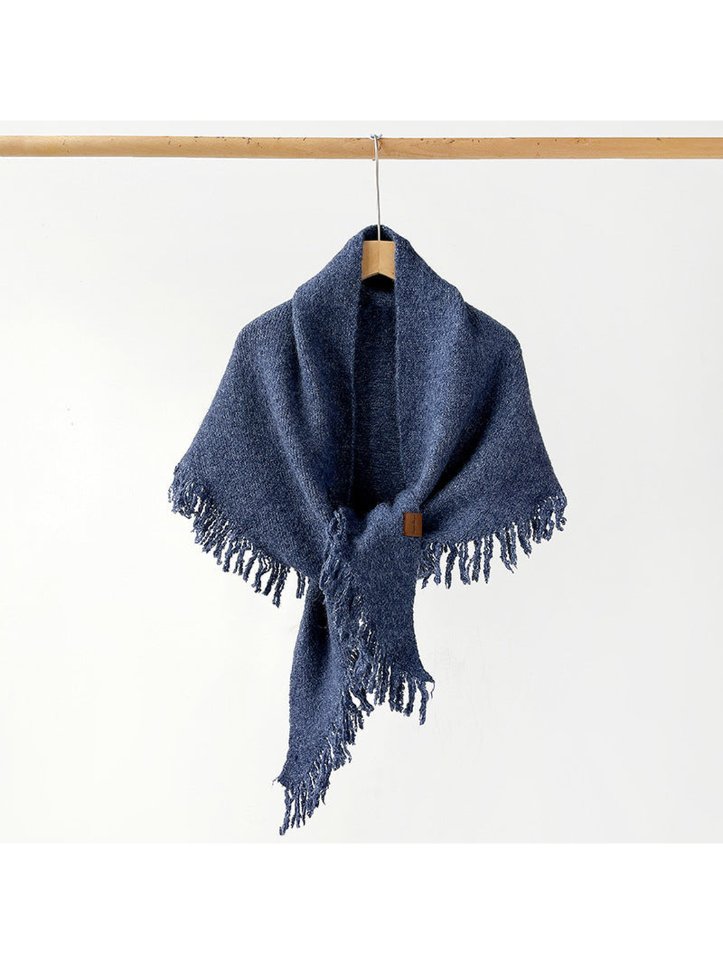 Navy fringed scarf draped and knotted on a hanger