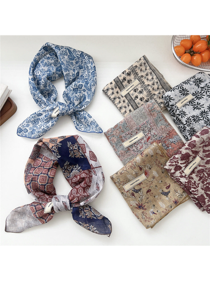 Assorted patterned square scarves folded and tied on a tabletop