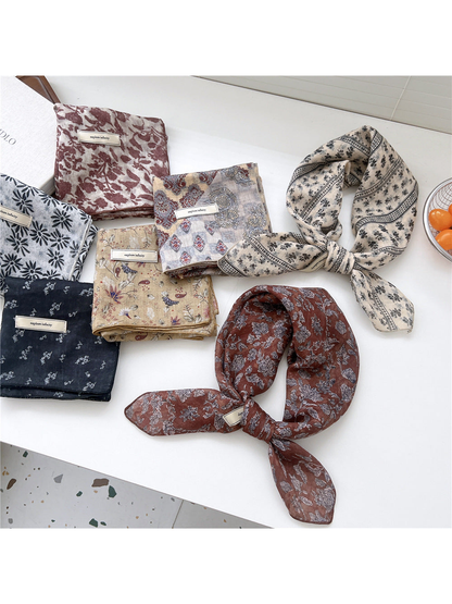 Assorted floral and striped square scarves arranged folded and tied