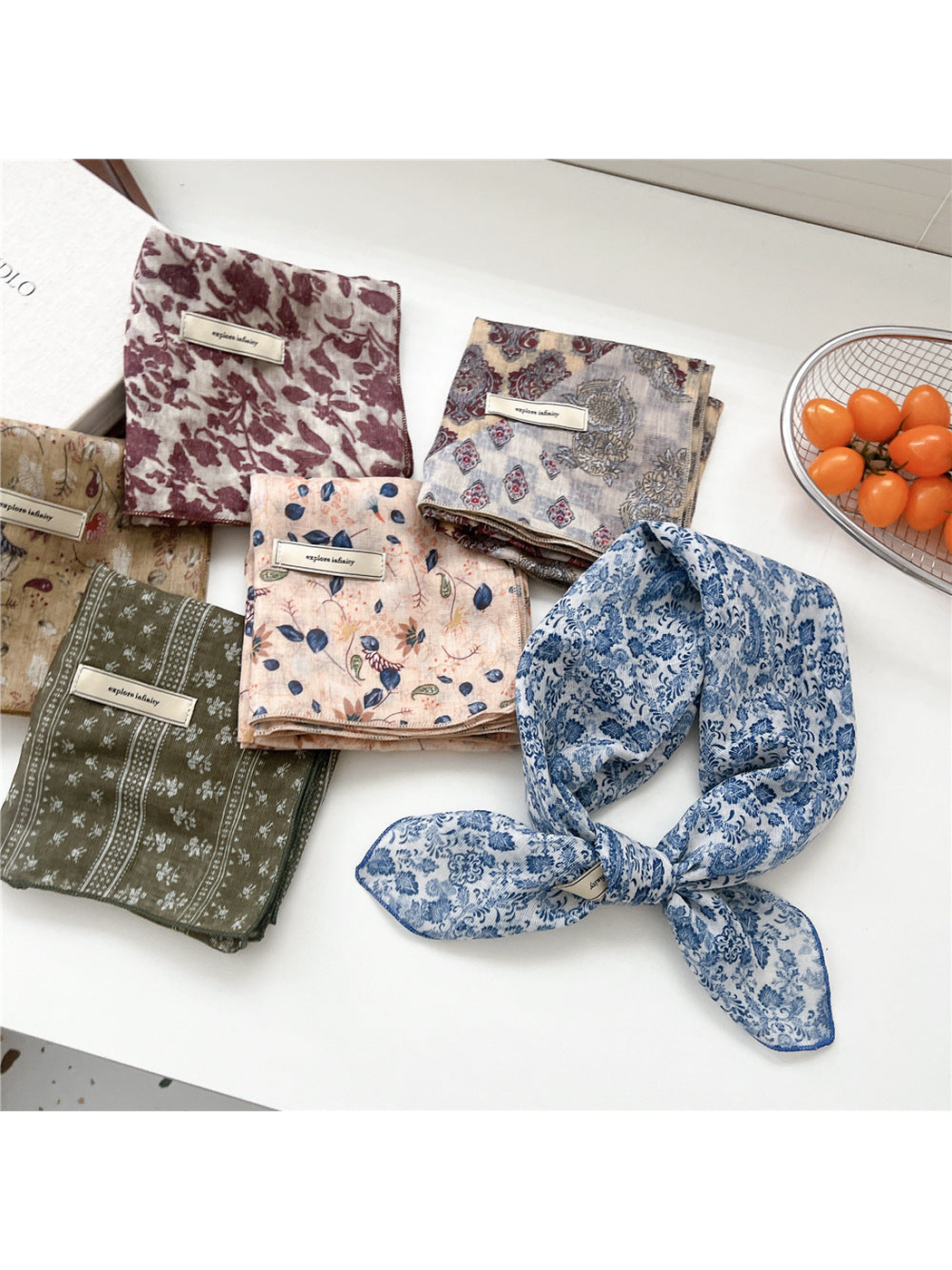 Blue floral square scarf tied beside assorted folded patterns