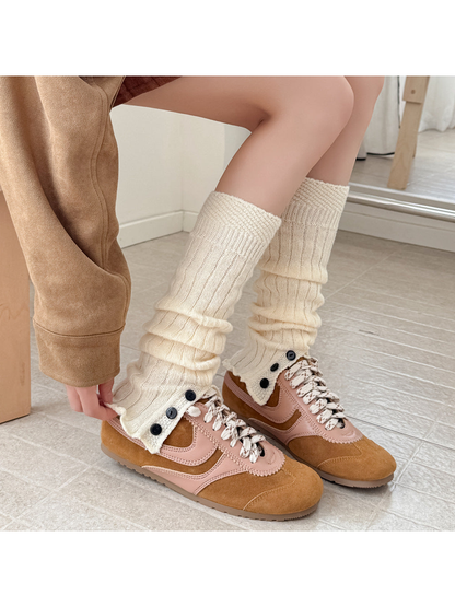 Cream ribbed leg warmers with black buttons worn with tan sneakers.