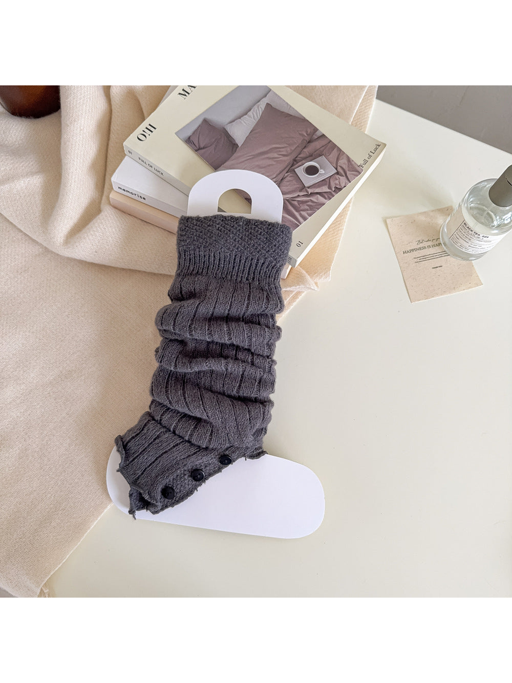 Dark gray ribbed leg warmer with a textured cuff and black button trim.