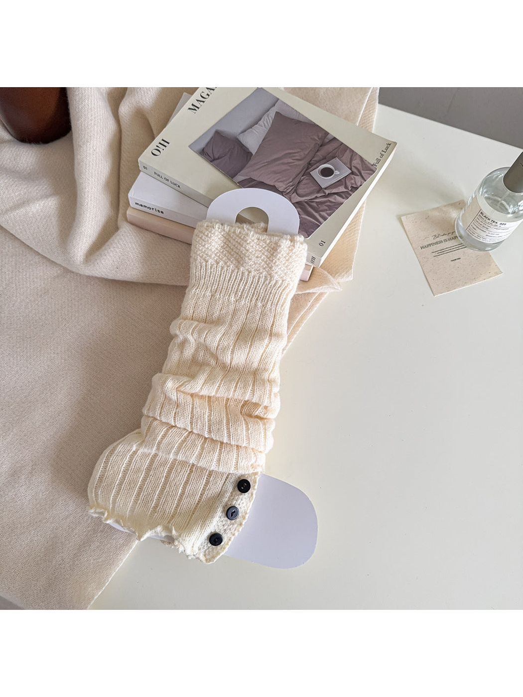 Cream ribbed leg warmer with a textured cuff and black button trim.