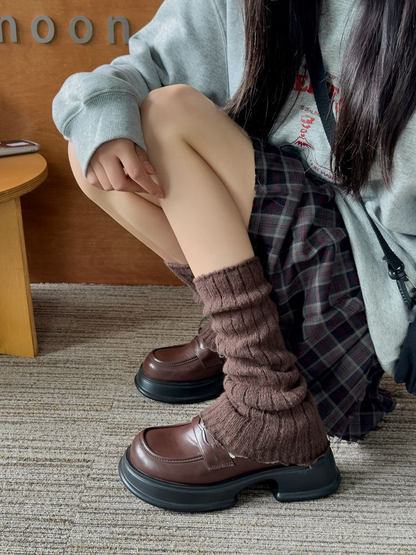 Coffee ribbed leg warmers worn with brown loafers while seated