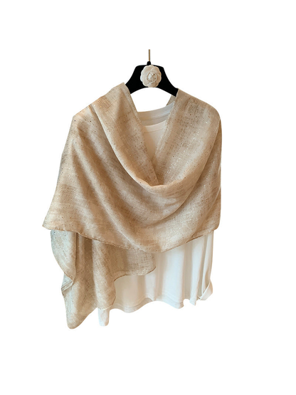 Beige rectangular scarf with metallic-look flecks draped over a white top