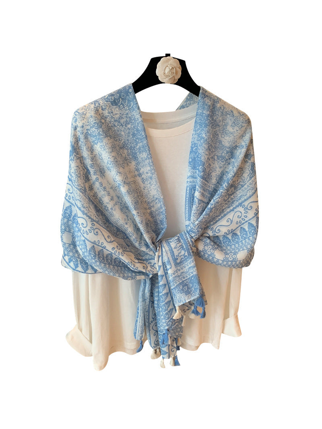 Light blue and ivory ornamental scarf tied over a white top with tassel ends