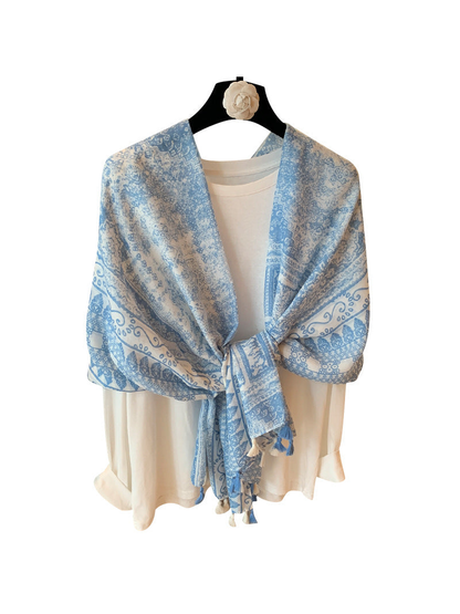 Light blue and ivory ornamental scarf tied over a white top with tassel ends