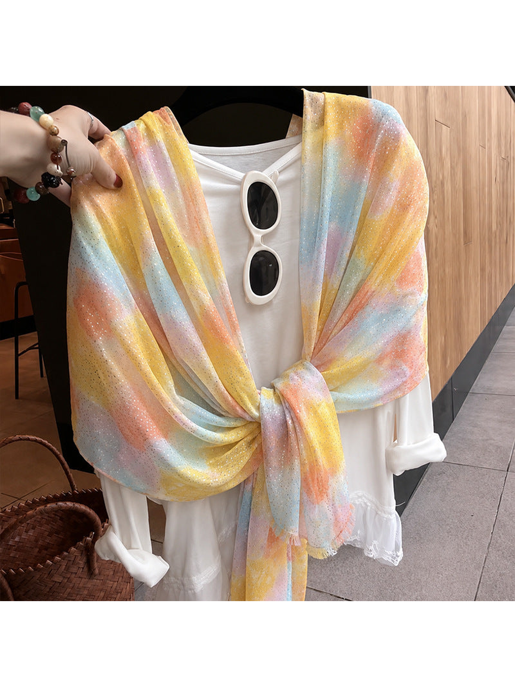 Multicolor watercolor-pattern scarf tied over a white top on a hanger