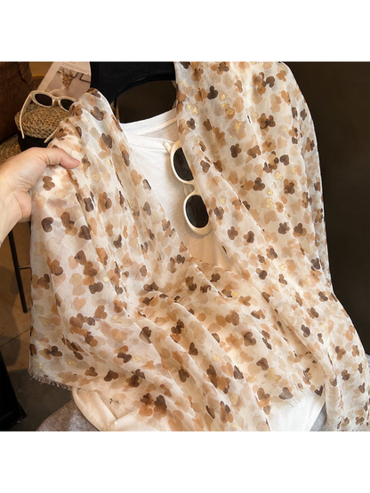 Close-up of the semi-sheer beige scarf with scattered heart-like motifs