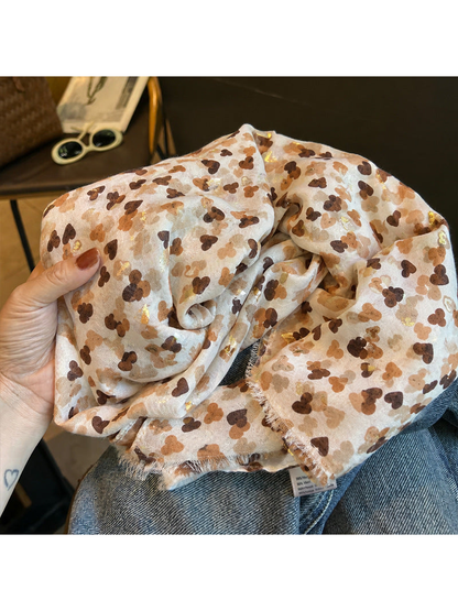 Close-up of the beige patterned scarf with gold-tone accents and short fringe
