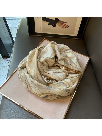 Khaki abstract-pattern scarf arranged in a loose loop on a display tray
