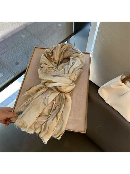Khaki abstract-pattern scarf tied in a loose knot on a display tray