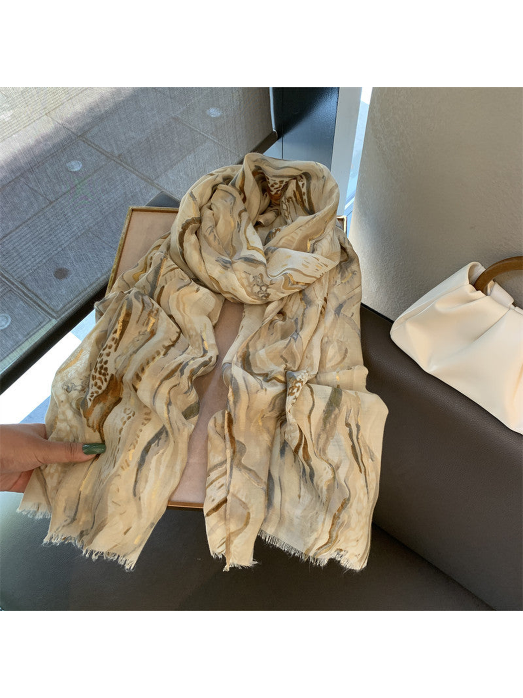 Khaki abstract-pattern scarf loosely draped across a display tray