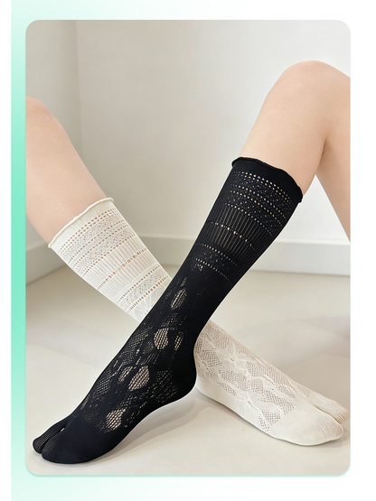 Black and ivory floral openwork split-toe knee-high socks worn with crossed legs