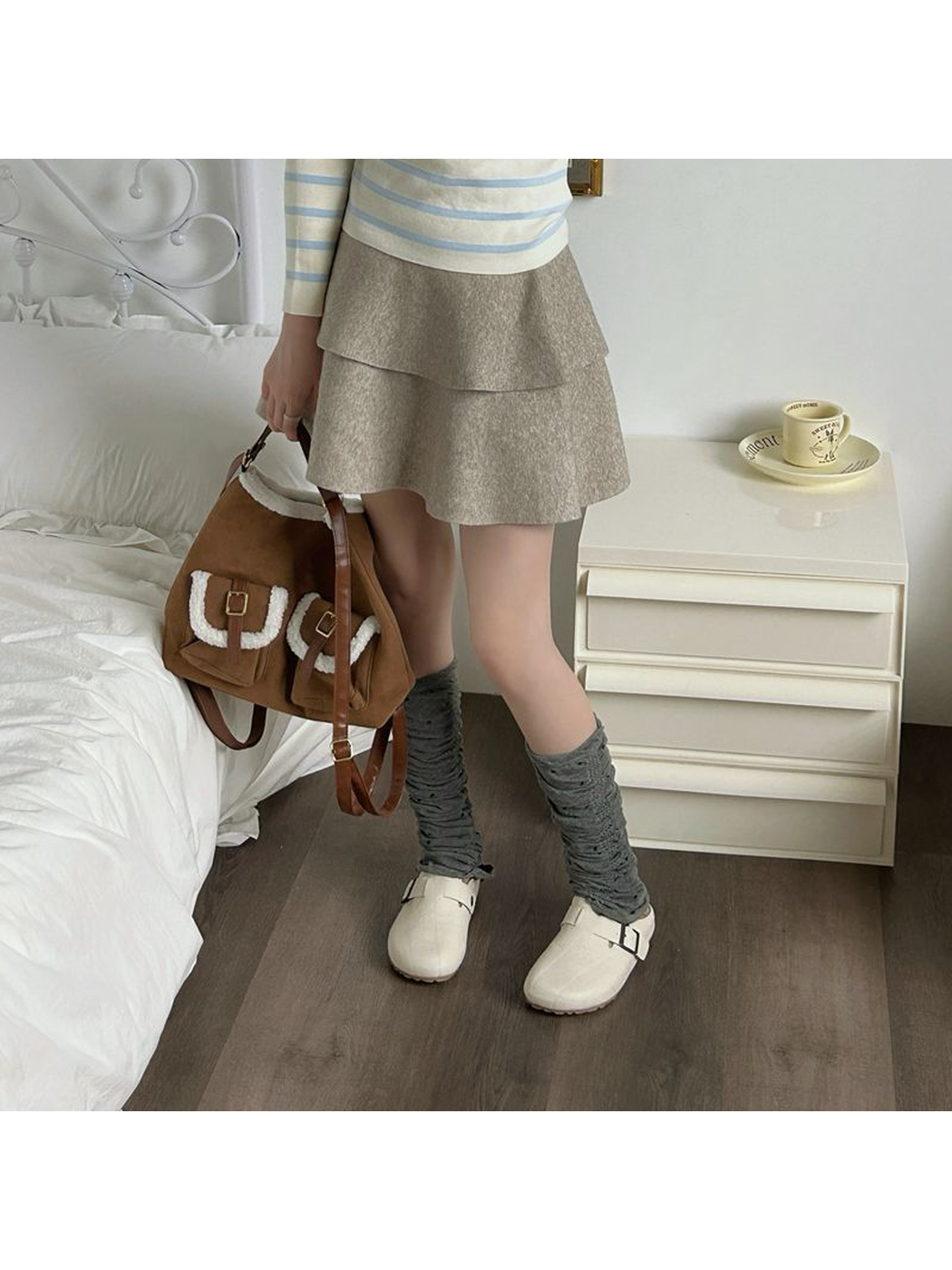 Gray polka-dot ruched leg warmers worn with white shoes in a standing view