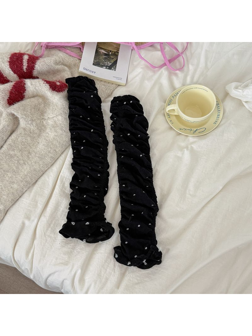 Black polka-dot ruched leg warmers laid flat as a pair