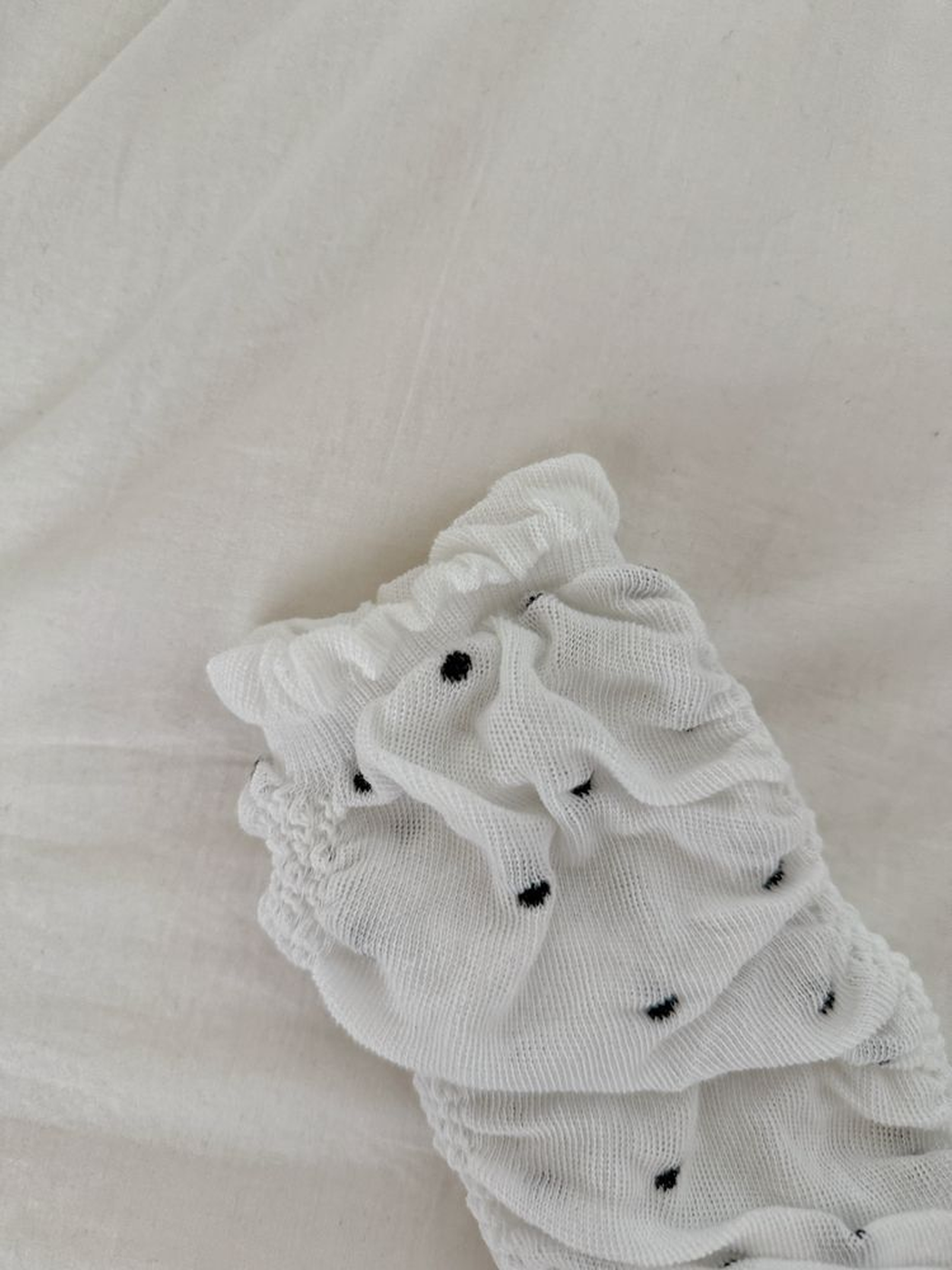 Close-up of the white polka-dot fabric, ruching and ruffled open edge