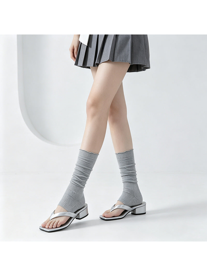 Gray ribbed open-toe mid-calf socks worn with silver sandals, standing view