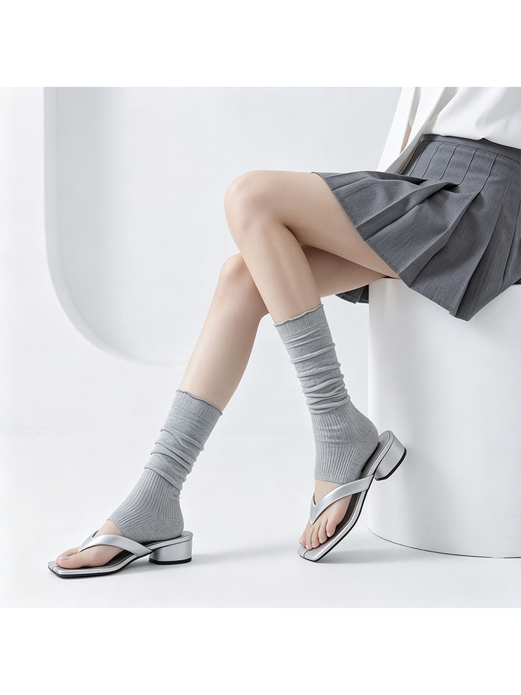 Gray ribbed open-toe mid-calf socks worn with silver sandals in a seated pose