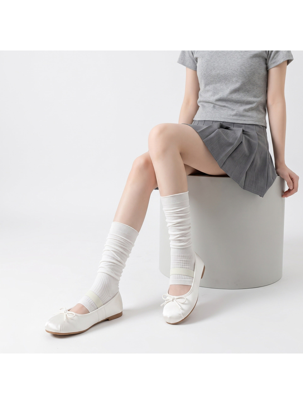 White ribbed open-toe mid-calf socks worn with ballet flats in a seated pose