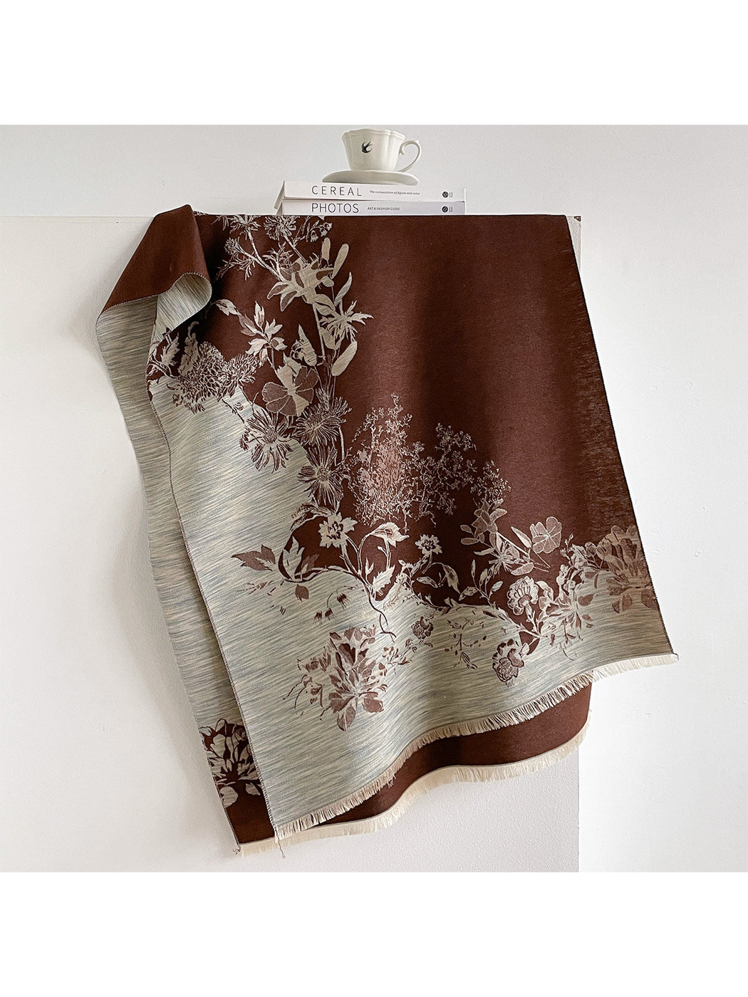 Brown floral scarf draped open with contrasting striped borders and short fringe.
