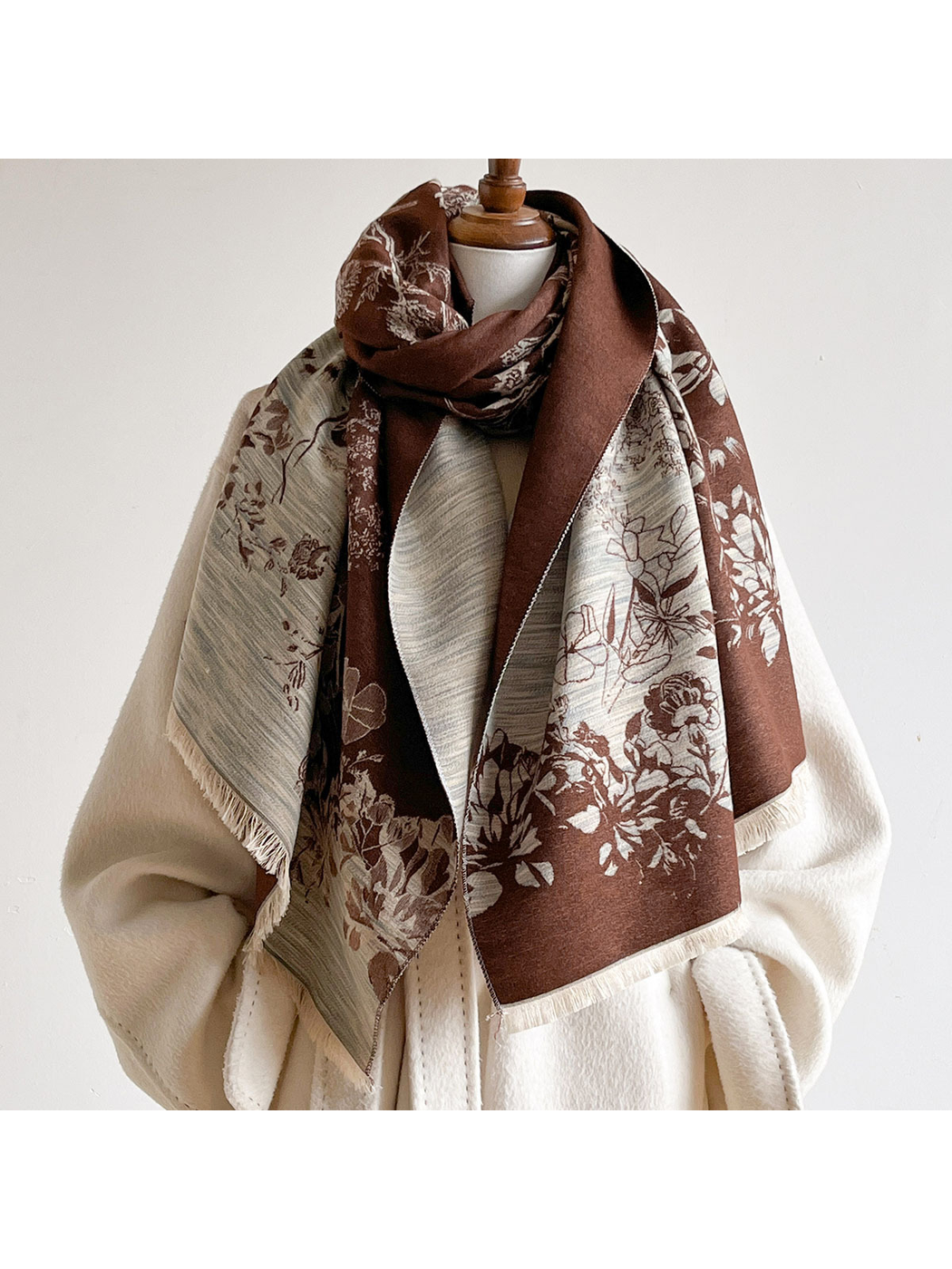 Brown floral scarf looped around a mannequin's neck with contrasting panels hanging over an ivory coat.