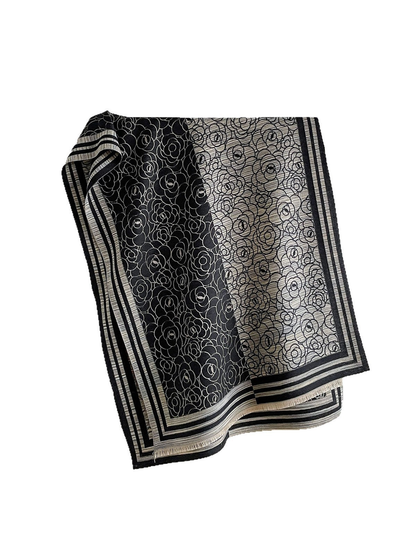 Black Gray floral scarf with contrasting panels, striped borders and short fringe, draped against white.