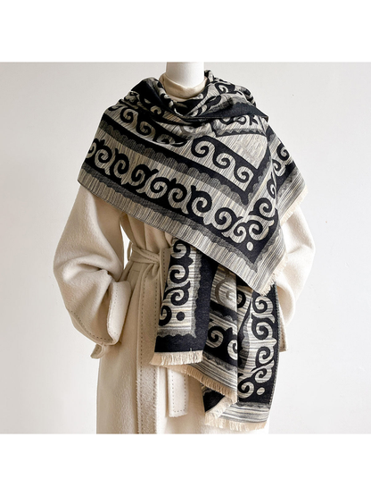 Black / Gray scroll-pattern scarf wrapped across the shoulders of a mannequin over a cream coat.