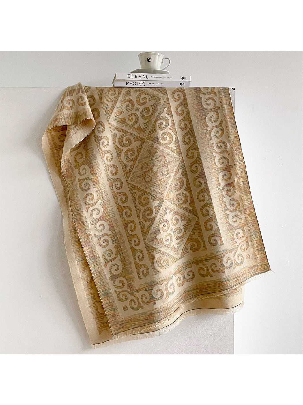 Multicolor scarf draped open with cream scroll motifs, muted colored striations, and short fringe.
