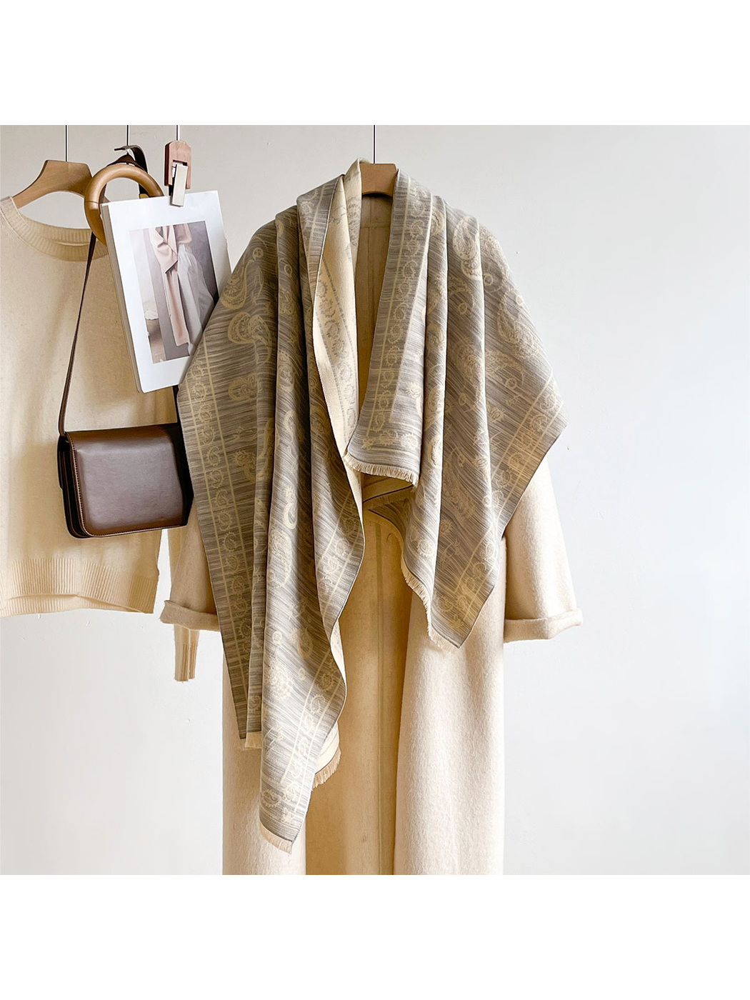 Light Gray paisley scarf hanging in a long draped display over a cream coat
